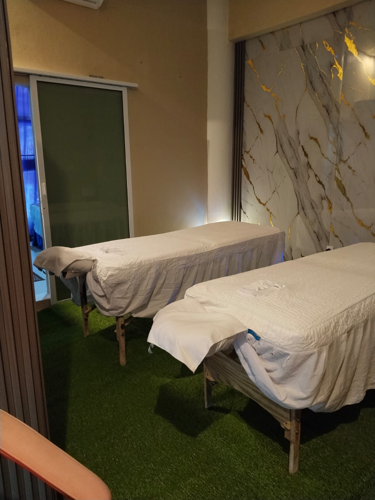 Dos camillas de masaje vestidas de blanco en la sala del spa, con luz cálida